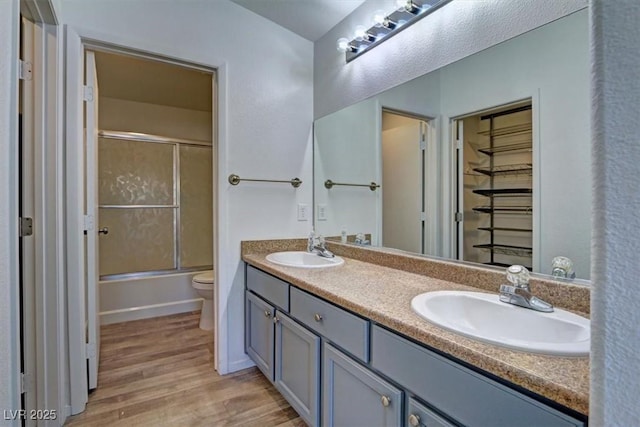 full bath featuring double vanity, wood finished floors, a sink, and toilet