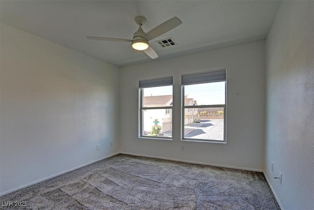 carpeted spare room featuring a ceiling fan, visible vents, and baseboards