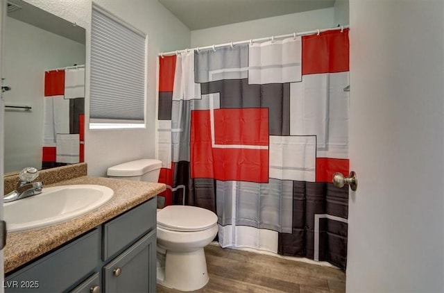 bathroom featuring toilet, curtained shower, wood finished floors, and vanity