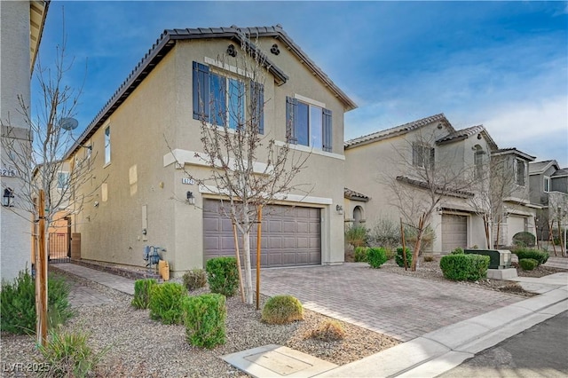 view of front of property featuring decorative driveway, an attached garage, a tile roof, and stucco siding