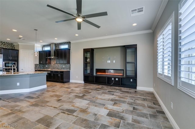 kitchen featuring visible vents, baseboards, open floor plan, decorative backsplash, and a glass covered fireplace