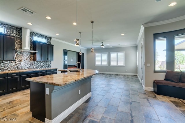 kitchen featuring a sink, visible vents, open floor plan, decorative backsplash, and wall chimney exhaust hood