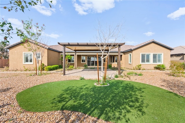 rear view of house featuring stucco siding, a tiled roof, a patio, and a yard