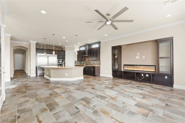 kitchen featuring open floor plan, stainless steel built in fridge, backsplash, visible vents, and wall chimney range hood
