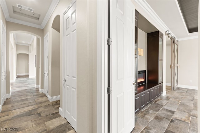 hallway featuring arched walkways, crown molding, baseboards, and visible vents