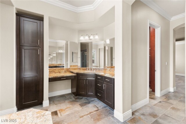 bathroom featuring baseboards, ornamental molding, and vanity