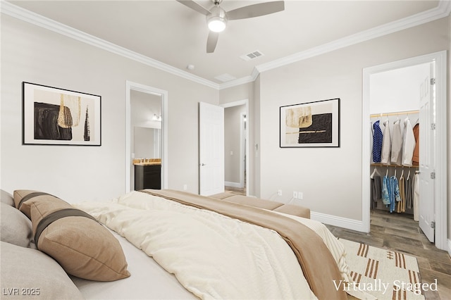 bedroom featuring a spacious closet, ornamental molding, baseboards, a closet, and wood finished floors
