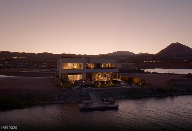 back of house at dusk featuring a water and mountain view