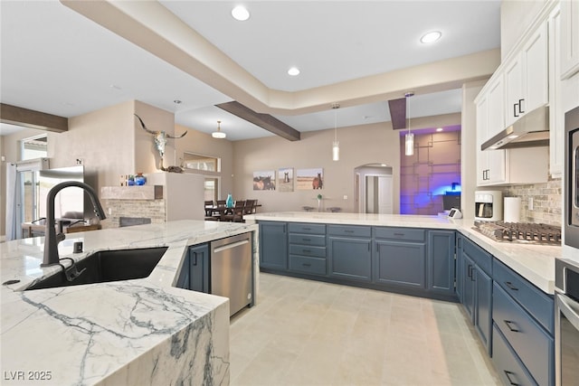 kitchen with a sink, stainless steel appliances, a peninsula, white cabinets, and decorative backsplash