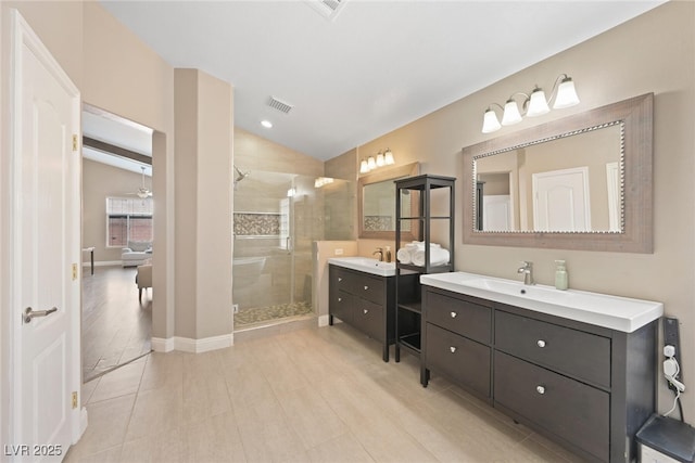 bathroom featuring visible vents, two vanities, a stall shower, a sink, and vaulted ceiling