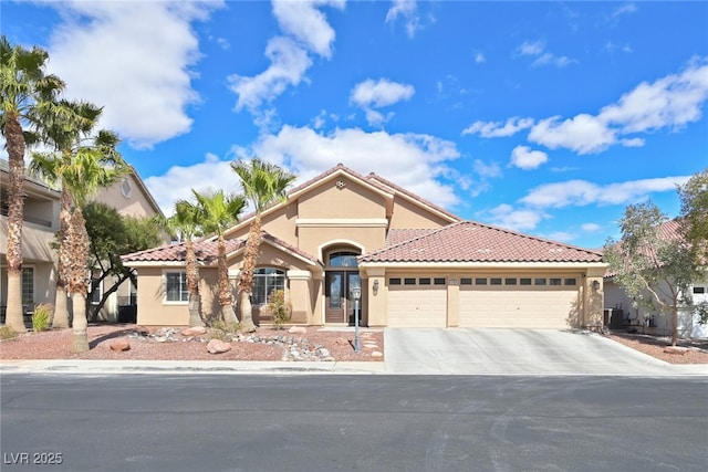 mediterranean / spanish-style house featuring a tile roof, an attached garage, concrete driveway, and stucco siding