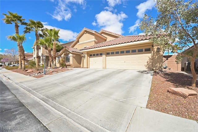 mediterranean / spanish-style house with a tiled roof, stucco siding, an attached garage, and driveway