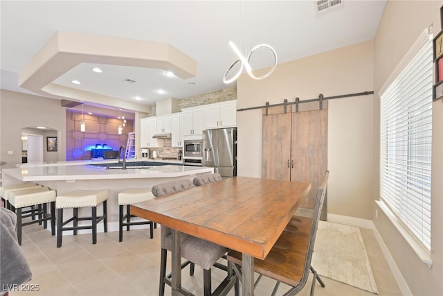 dining area featuring visible vents, baseboards, a barn door, light tile patterned floors, and arched walkways