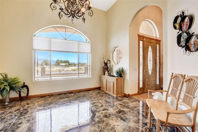 entryway with baseboards, arched walkways, a towering ceiling, marble finish floor, and a notable chandelier