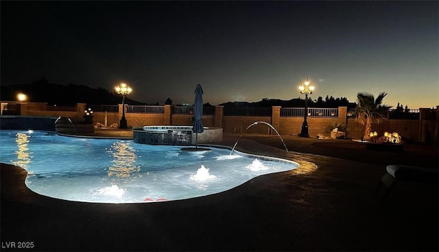 pool at twilight with a fenced backyard and a pool with connected hot tub