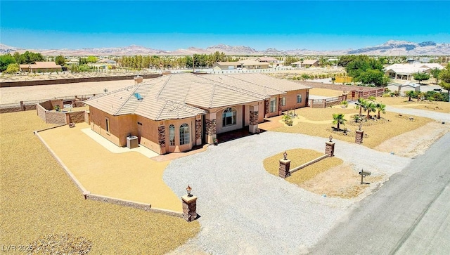 view of front facade featuring driveway, a tile roof, fence, and a mountain view