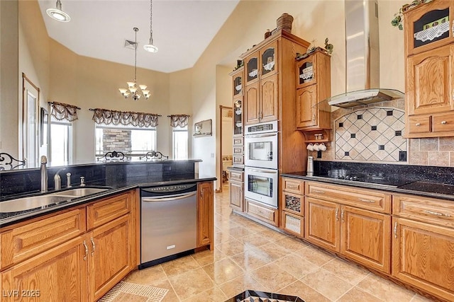 kitchen with decorative light fixtures, stainless steel appliances, backsplash, a sink, and wall chimney range hood