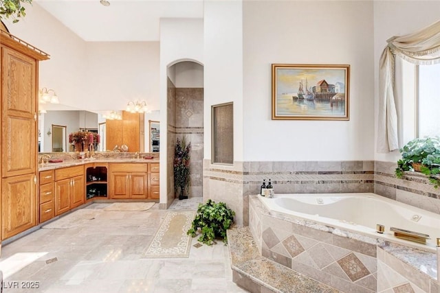 bathroom featuring a garden tub, tiled shower, and vanity