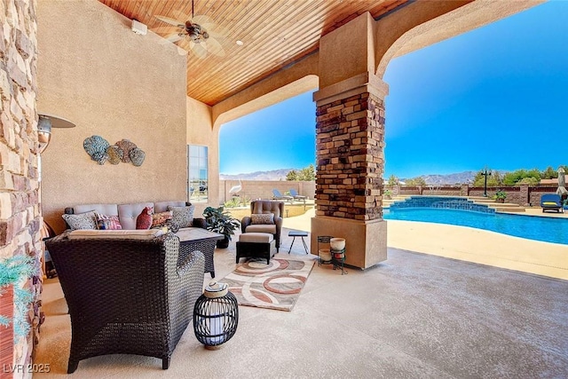 view of patio with a ceiling fan, a fenced in pool, fence, a mountain view, and outdoor lounge area