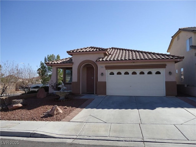 mediterranean / spanish house with an attached garage, a tile roof, concrete driveway, and stucco siding