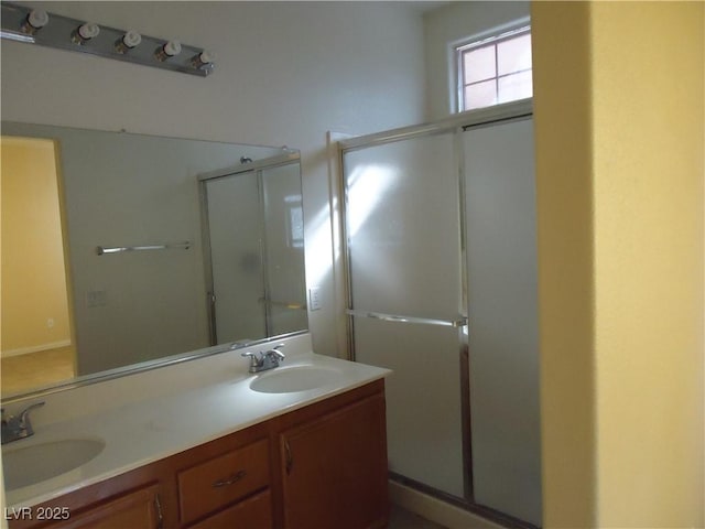 full bathroom with double vanity, a stall shower, and a sink