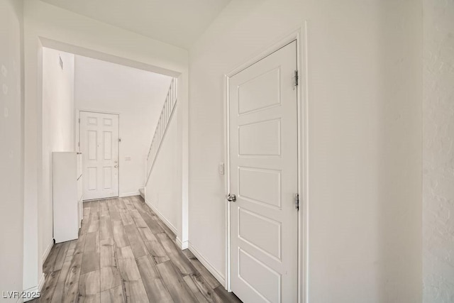 corridor featuring light wood finished floors and baseboards