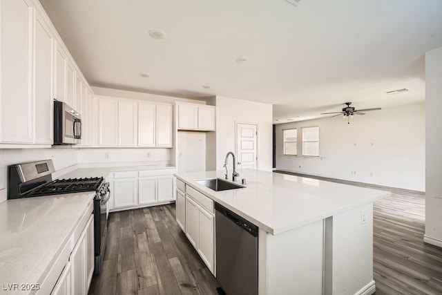 kitchen featuring dark wood-style floors, appliances with stainless steel finishes, white cabinets, and a sink