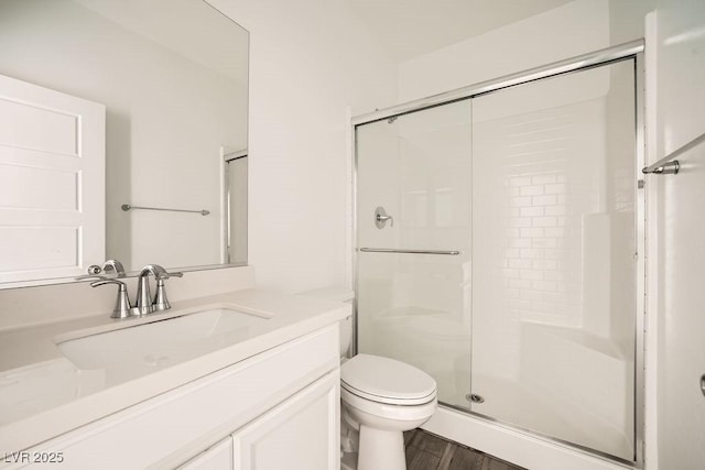 bathroom featuring toilet, a shower stall, and vanity