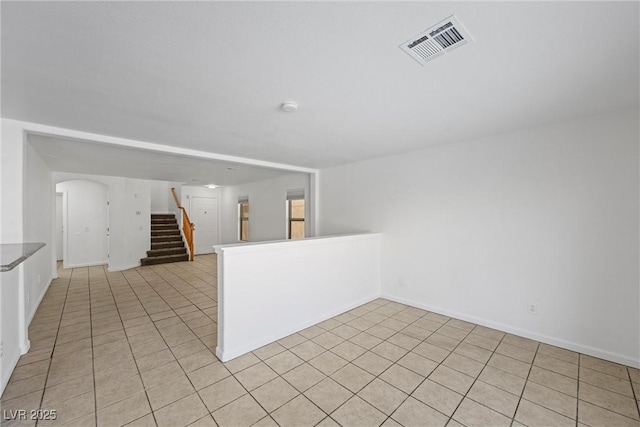 empty room featuring stairs, light tile patterned floors, and visible vents