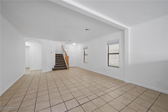 interior space with arched walkways, stairway, and baseboards