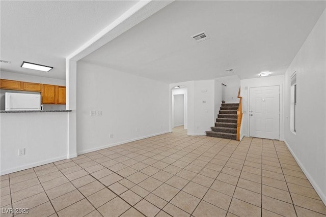 unfurnished living room with stairs, visible vents, and baseboards