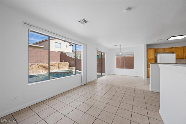 empty room featuring light tile patterned floors, baseboards, and visible vents