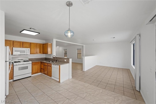 kitchen featuring white appliances, open floor plan, a peninsula, hanging light fixtures, and a sink