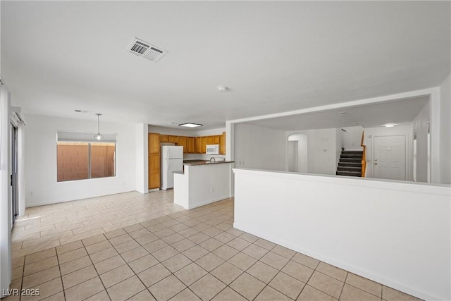 empty room featuring stairs, visible vents, and light tile patterned flooring