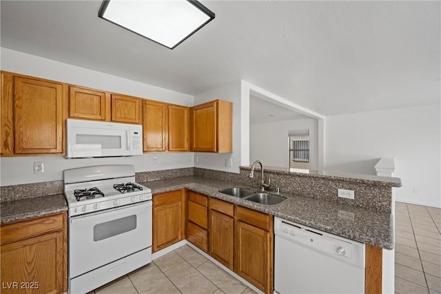 kitchen with light tile patterned floors, a peninsula, white appliances, and a sink