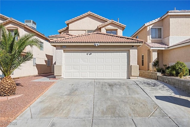 mediterranean / spanish house with a garage, a tile roof, concrete driveway, and stucco siding