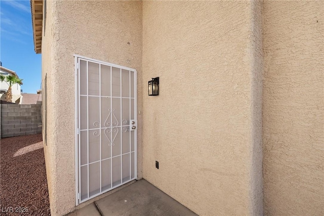 entrance to property with fence and stucco siding