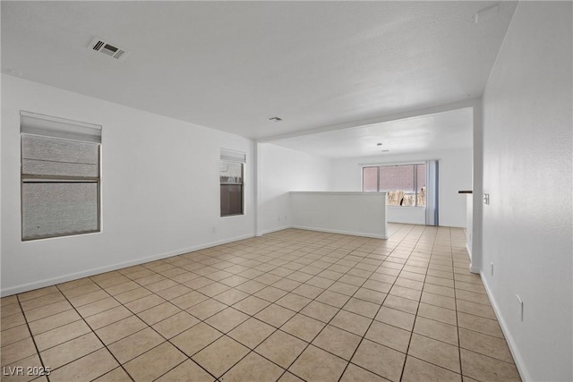 empty room featuring light tile patterned floors, visible vents, and baseboards