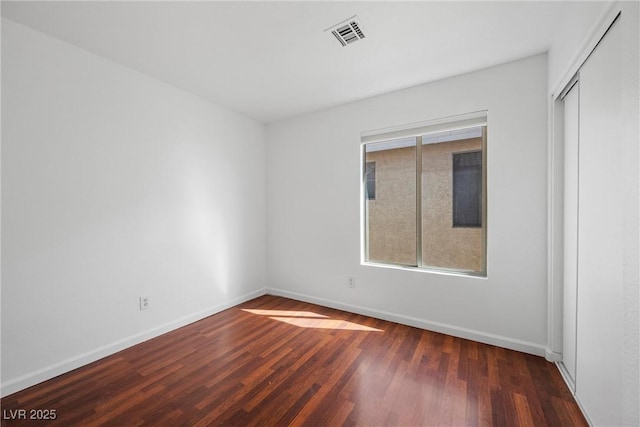 unfurnished room featuring visible vents, baseboards, and wood finished floors