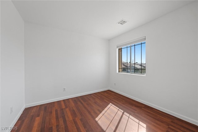 spare room with baseboards, visible vents, and wood finished floors