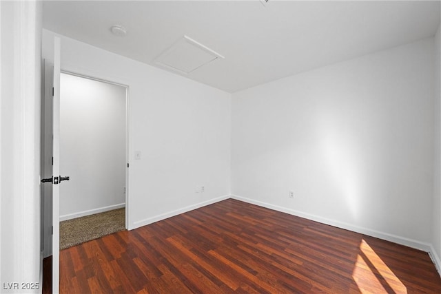 unfurnished room with attic access, baseboards, and wood finished floors