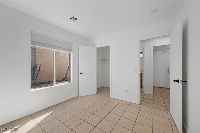 unfurnished bedroom featuring light tile patterned floors, baseboards, visible vents, and a closet