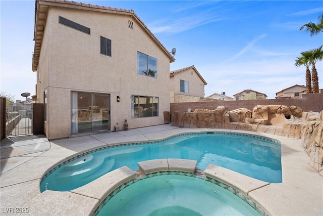 view of pool with a gate, a patio area, fence, and a pool with connected hot tub