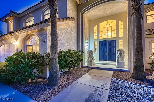 entrance to property featuring a tiled roof and stucco siding