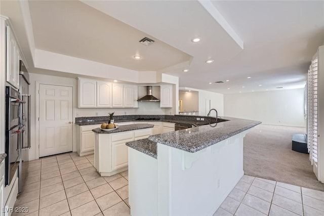 kitchen with black cooktop, a kitchen island, a sink, visible vents, and wall chimney exhaust hood