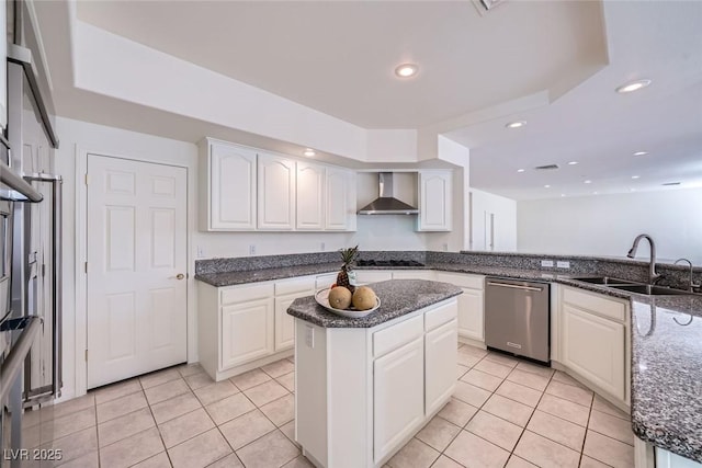 kitchen with light tile patterned floors, a sink, stainless steel dishwasher, wall chimney exhaust hood, and dark stone countertops