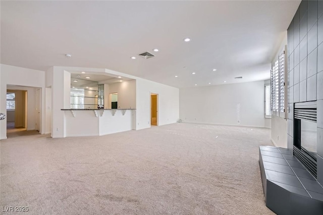 living area featuring recessed lighting, a fireplace, visible vents, and light colored carpet