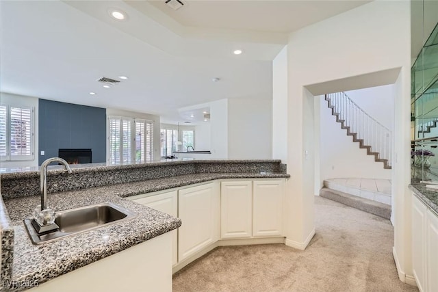 kitchen with a healthy amount of sunlight, a sink, visible vents, and light colored carpet