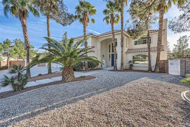 mediterranean / spanish-style house with a tiled roof, a gate, and stucco siding