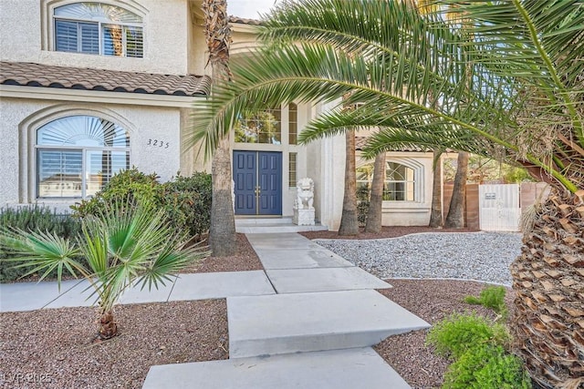 view of exterior entry with a tile roof and stucco siding